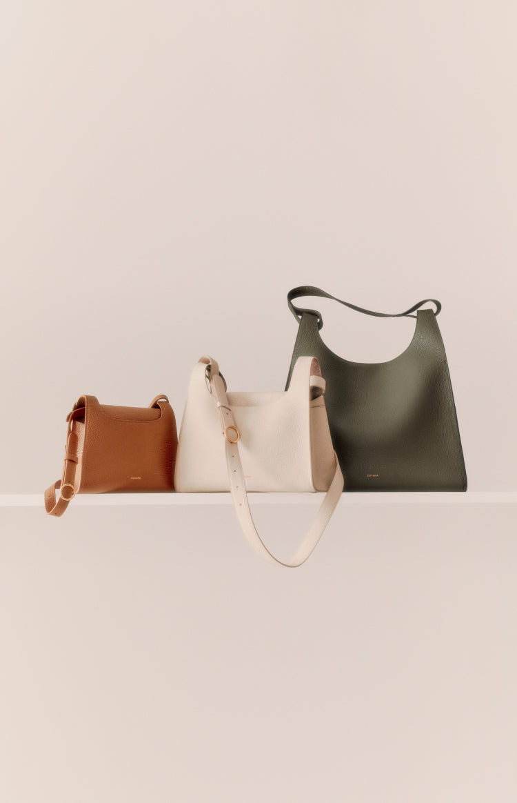 Three handbags of varying sizes and styles arranged on a shelf.