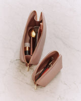 Two open cosmetic bags with makeup items inside on a marble surface.