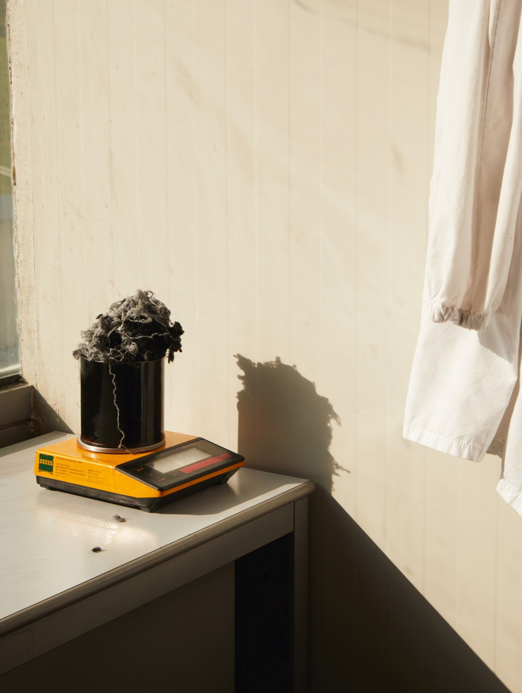 Plant in a pot on books near a window with a hanging curtain.