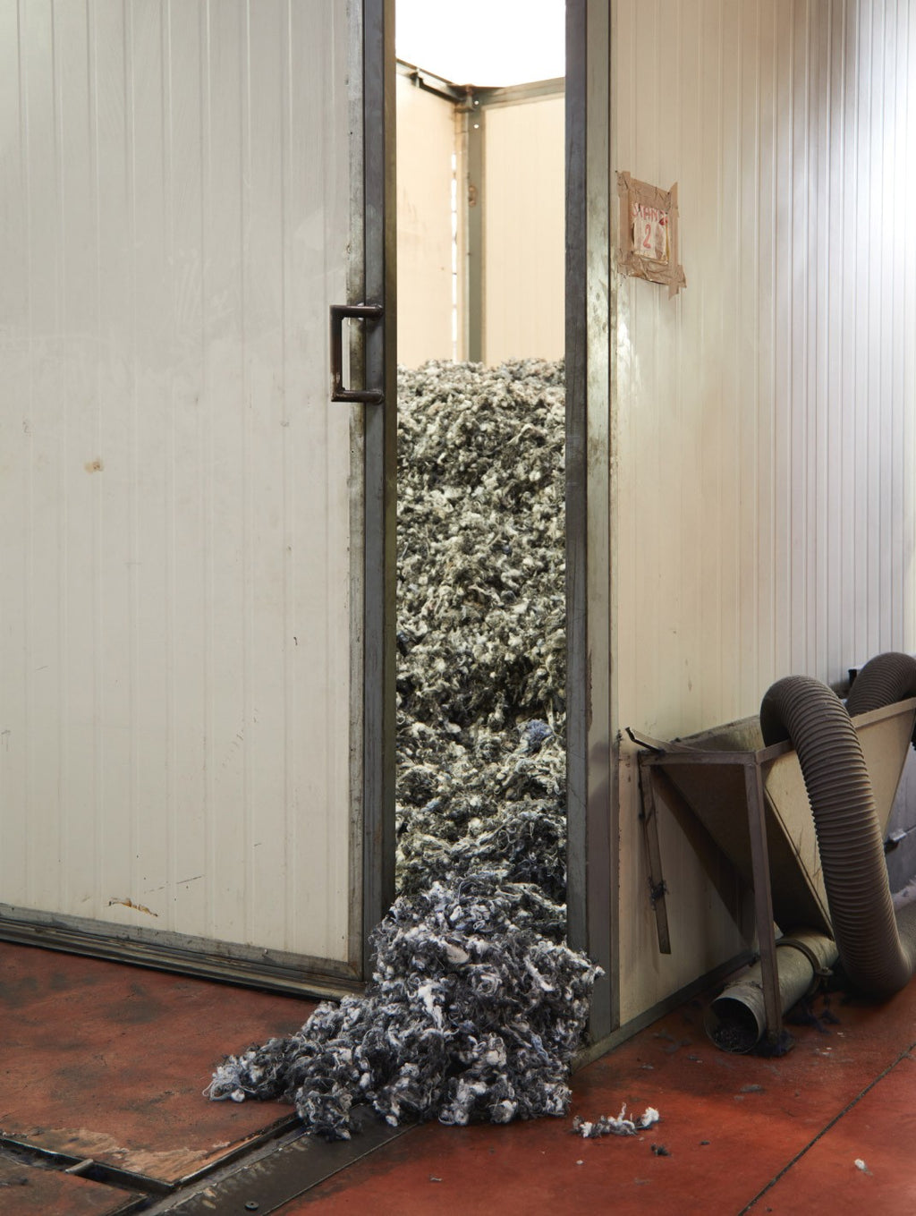 Open door with a pile of shredded material spilling out onto the floor.