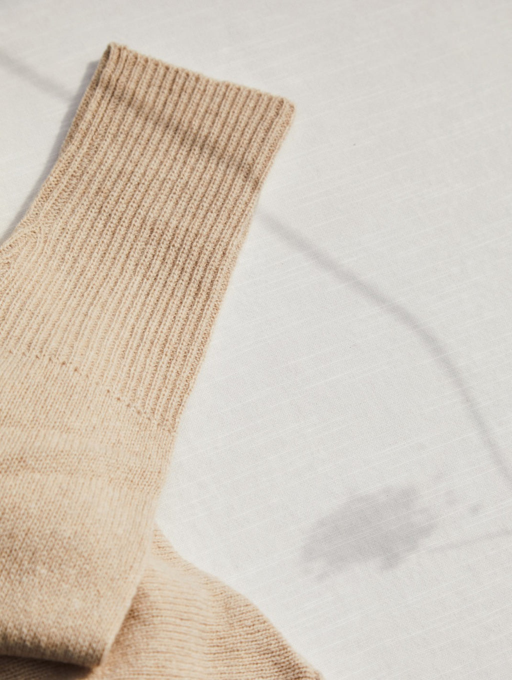 Close-up of a sock on a flat surface with shadows.