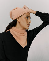 Woman in a beanie and sweater posing with hand on head