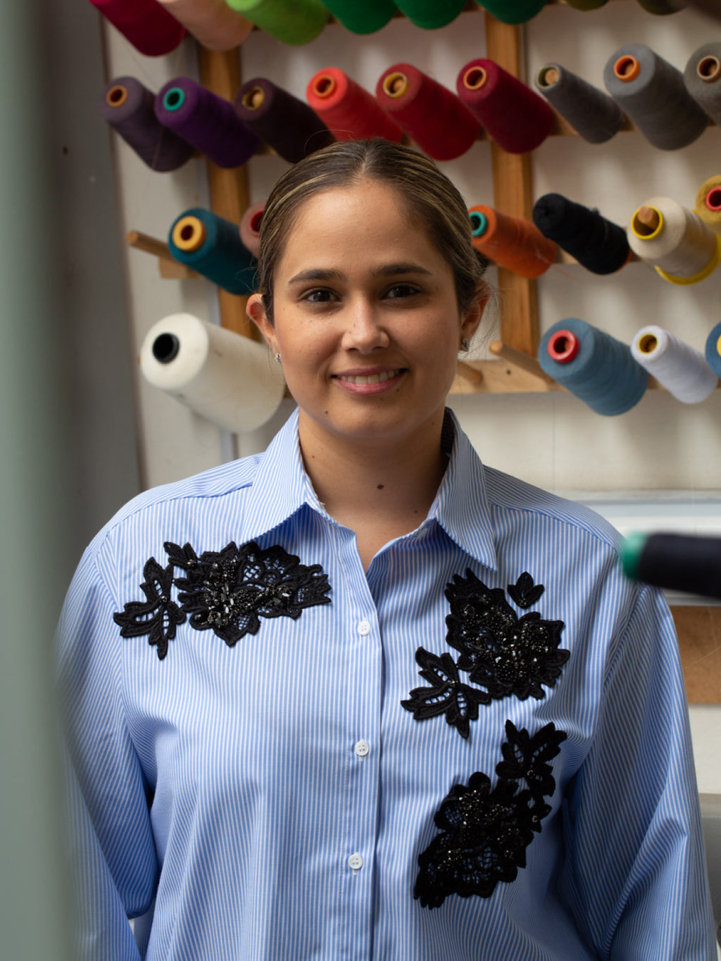 Woman standing in front of a rack of thread spools