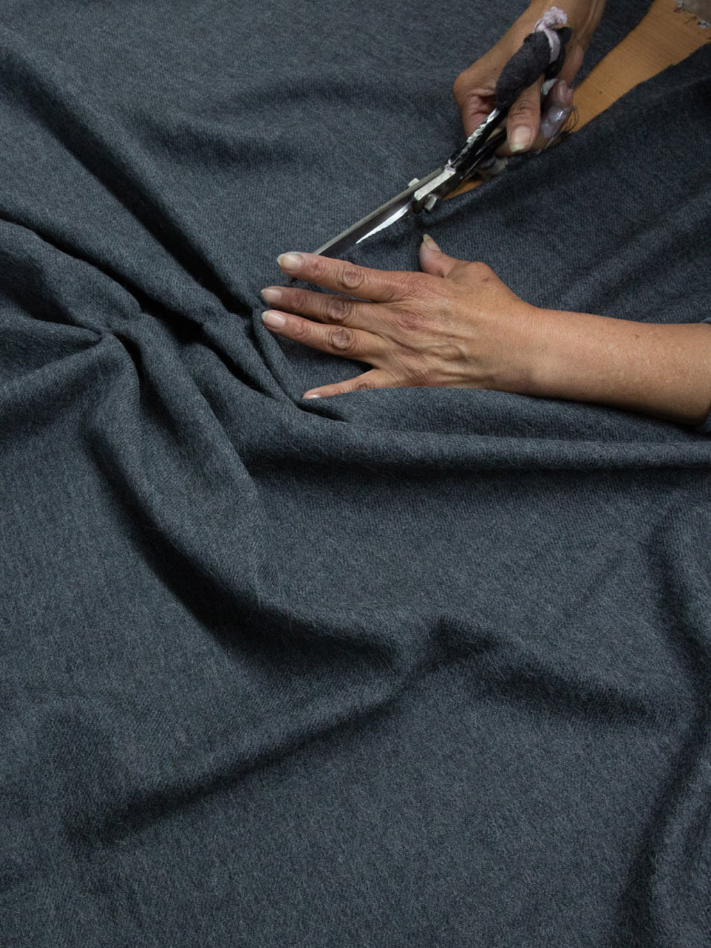 Person cutting fabric with scissors.