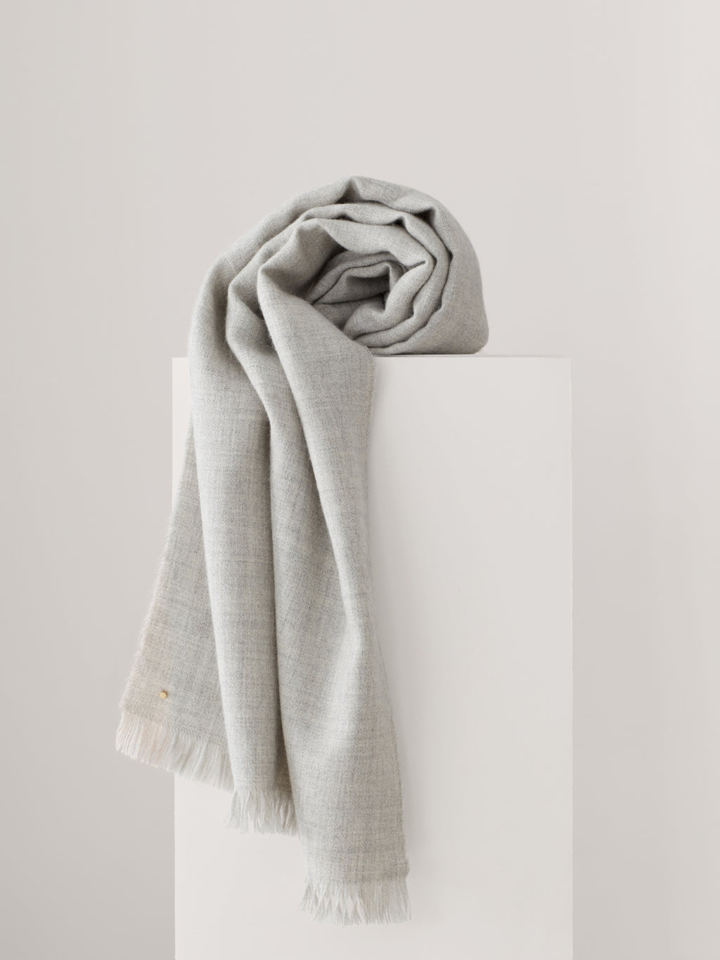 Scarf draped over a rectangular block against a plain background.