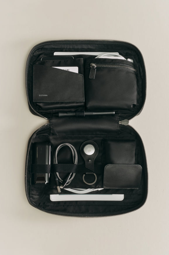 Organizer case open with various items including notebook, pen, and cables.