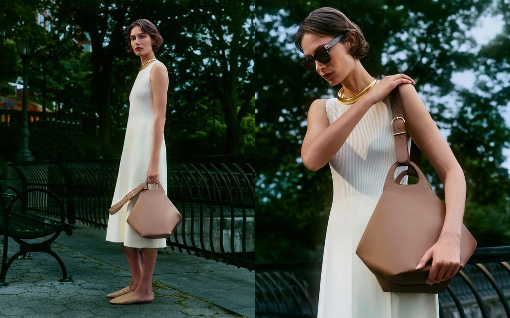 Woman in a sleeveless white dress holding a structured handbag outdoors.