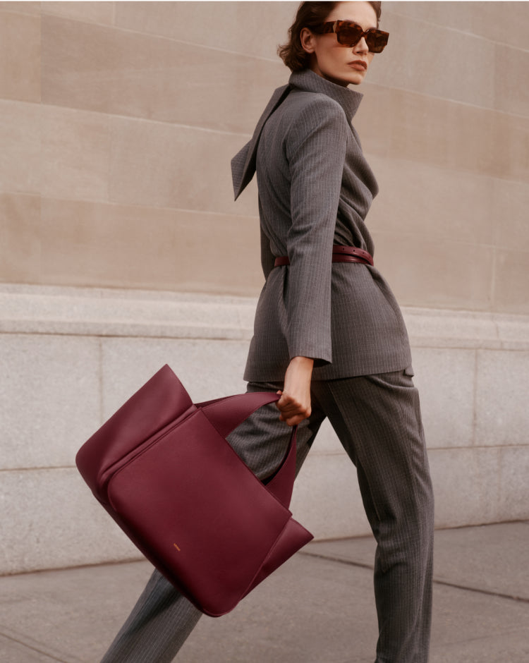 Person in suit walks holding a large bag.
