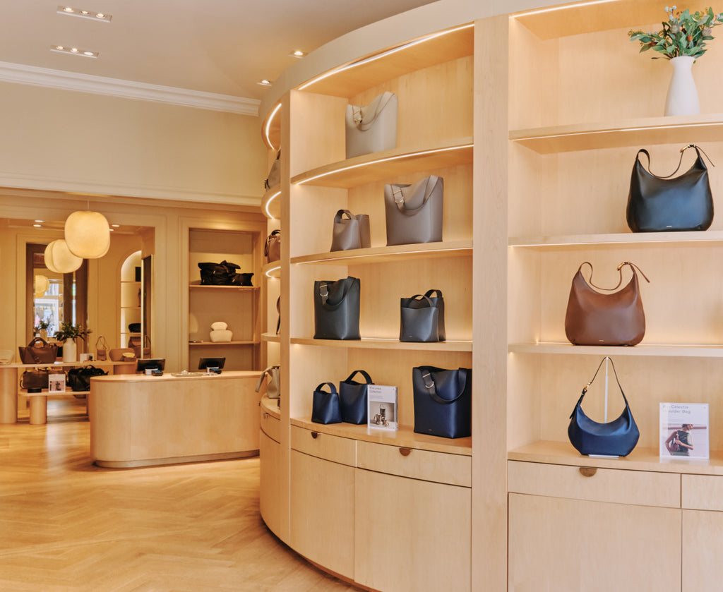 Store interior with shelves displaying handbags and a counter in the background.