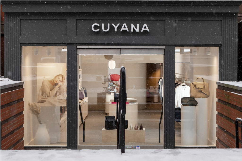 Storefront of Cuyana with visible interior including displayed bags and two mannequins.