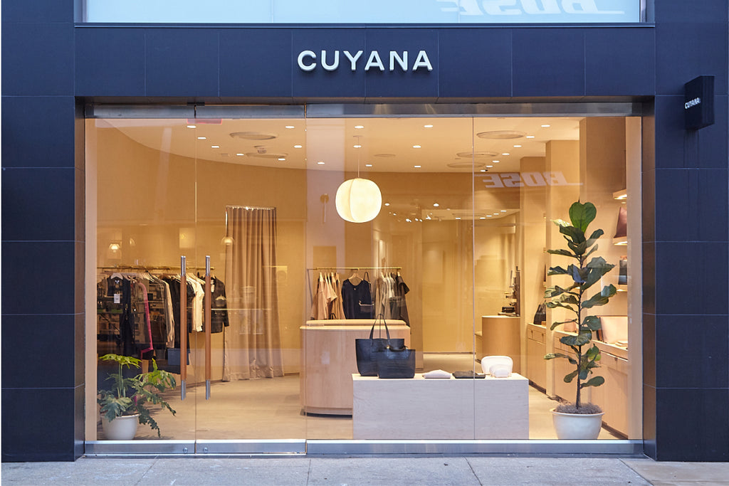 Storefront of Cuyana with visible interior including clothing racks and a plant.