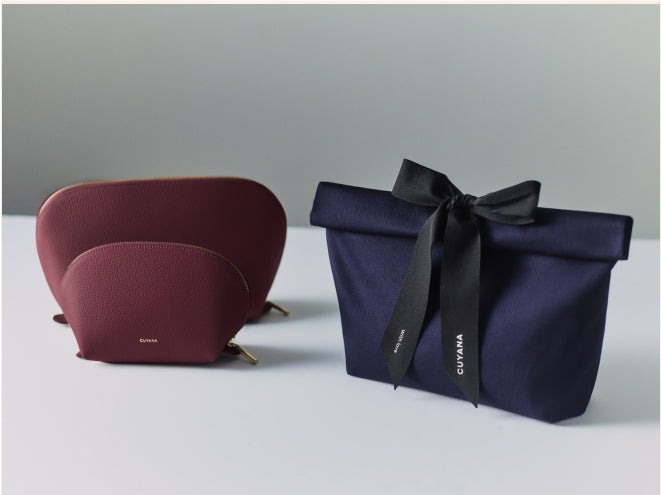 Two leather pouches and fabric gift bag with a tied ribbon.