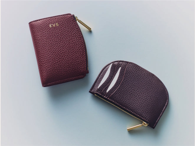 Two leather wallets with gold zippers on a flat surface.