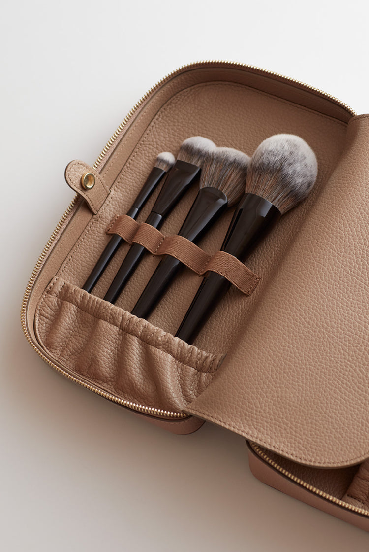 Makeup brushes in a small open case with straps securing them.