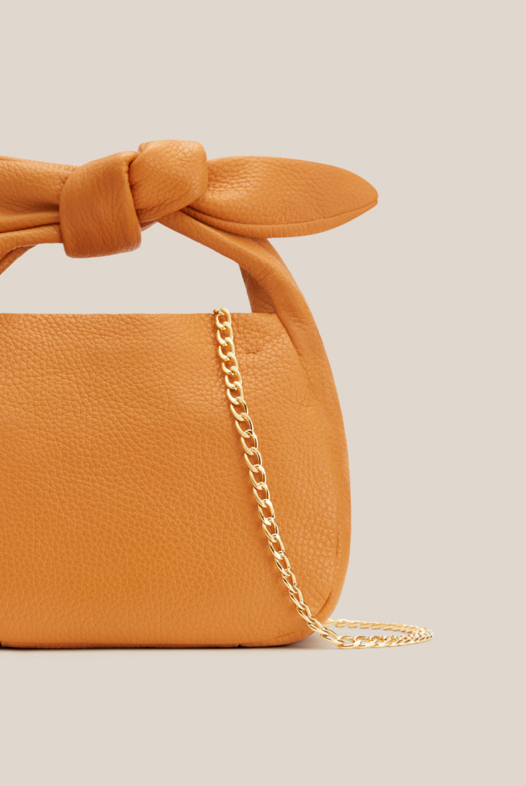 Handbag with knotted handle and metal chain strap.