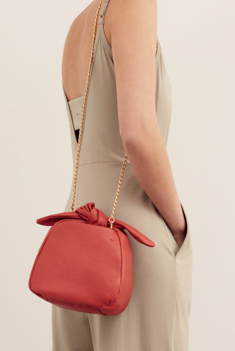 Woman holding a purse with a chain strap on her shoulder