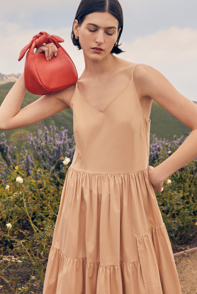 Woman in a dress holding a handbag outdoors
