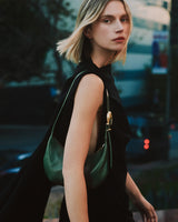 Woman in a sleeveless outfit with a shoulder bag on a city street.