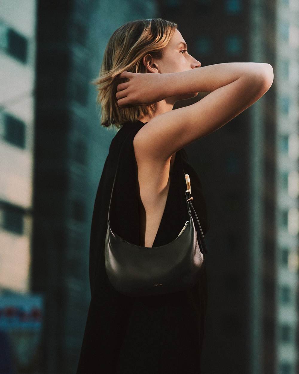 Person standing with shoulder bag in city environment