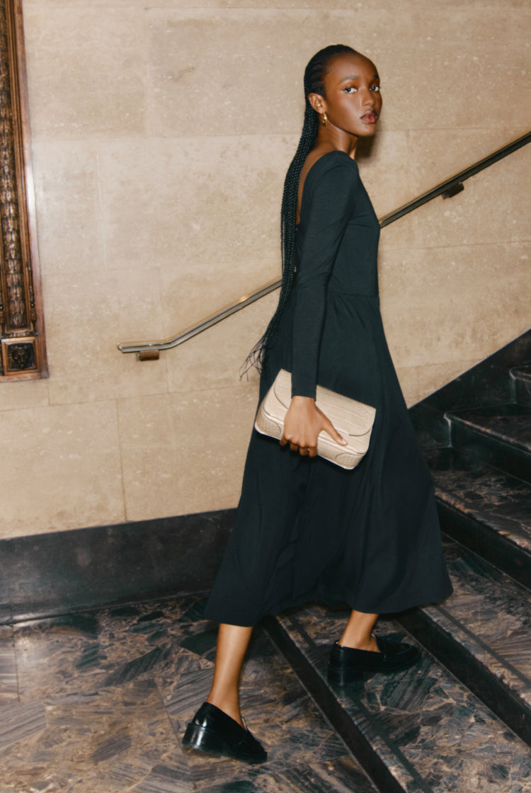 Woman walking down stairs holding a clutch bag.