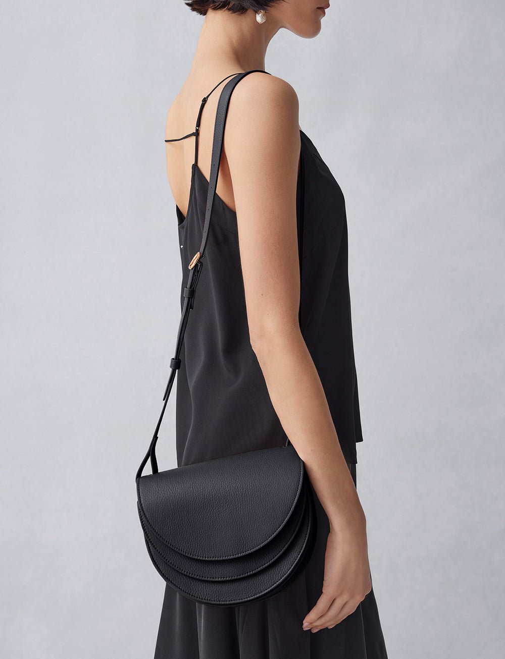 Person in a sleeveless outfit carrying a semicircular bag