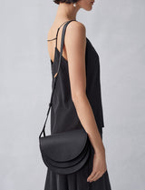 Person in a sleeveless outfit carrying a semicircular bag