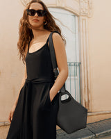 Woman wearing dress, sunglasses, and holding a handbag