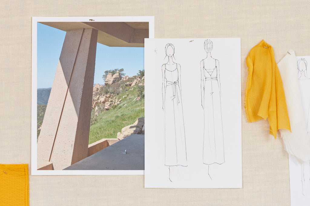 Mood board with landscape photo, fashion sketches, and hanging garments.