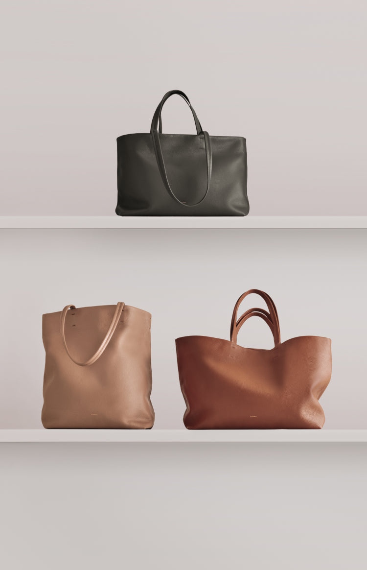 Three tote bags displayed on two shelves.