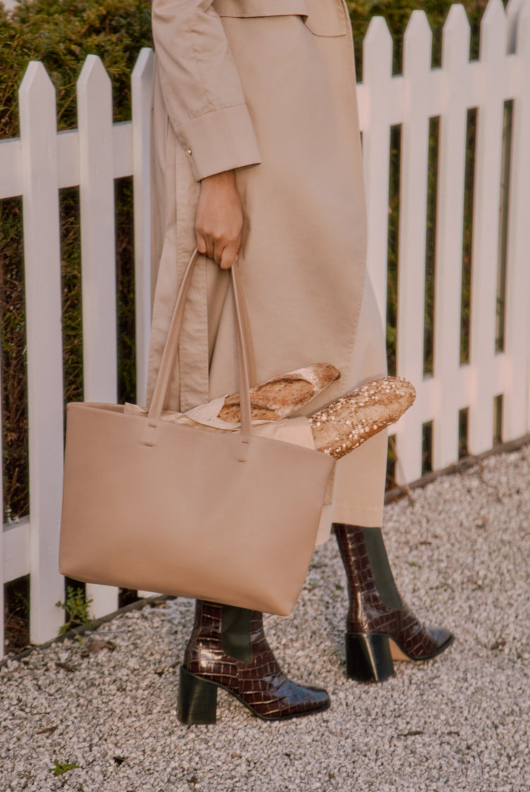 Person holding a bag with bread next to a white fence.