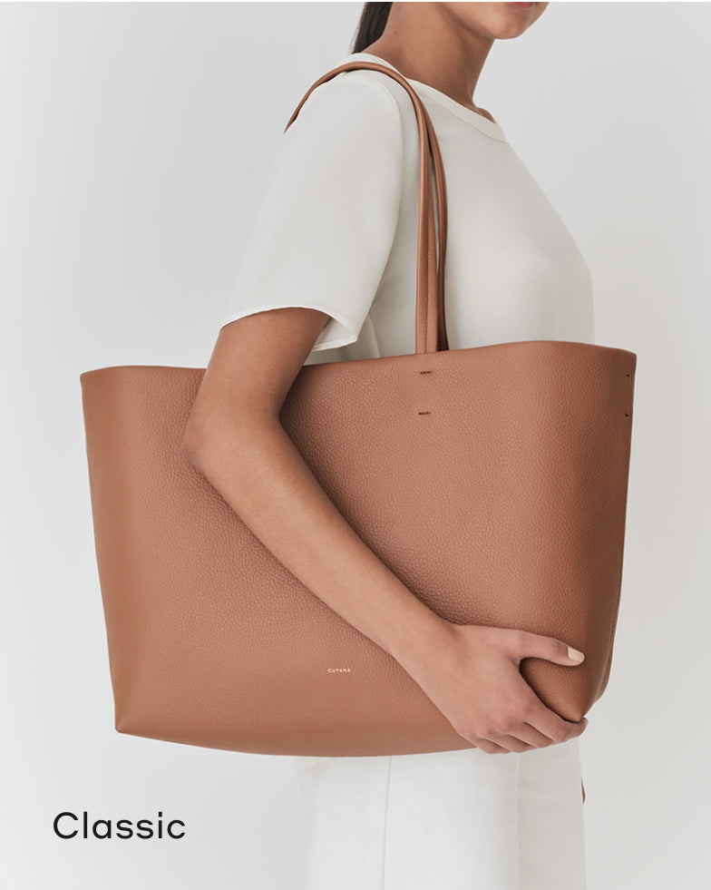 Woman holding a large handbag, viewed from the side.
