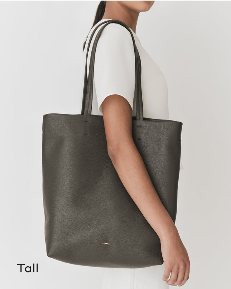 Person carrying a large tote bag over one shoulder.