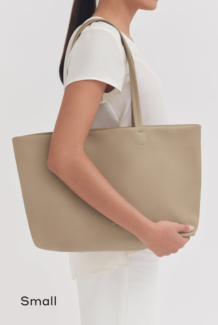 Woman holding a large tote bag on her shoulder.