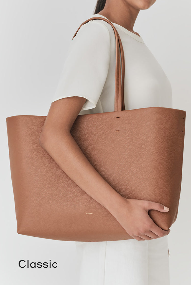 Woman holding a large tote bag on her shoulder.