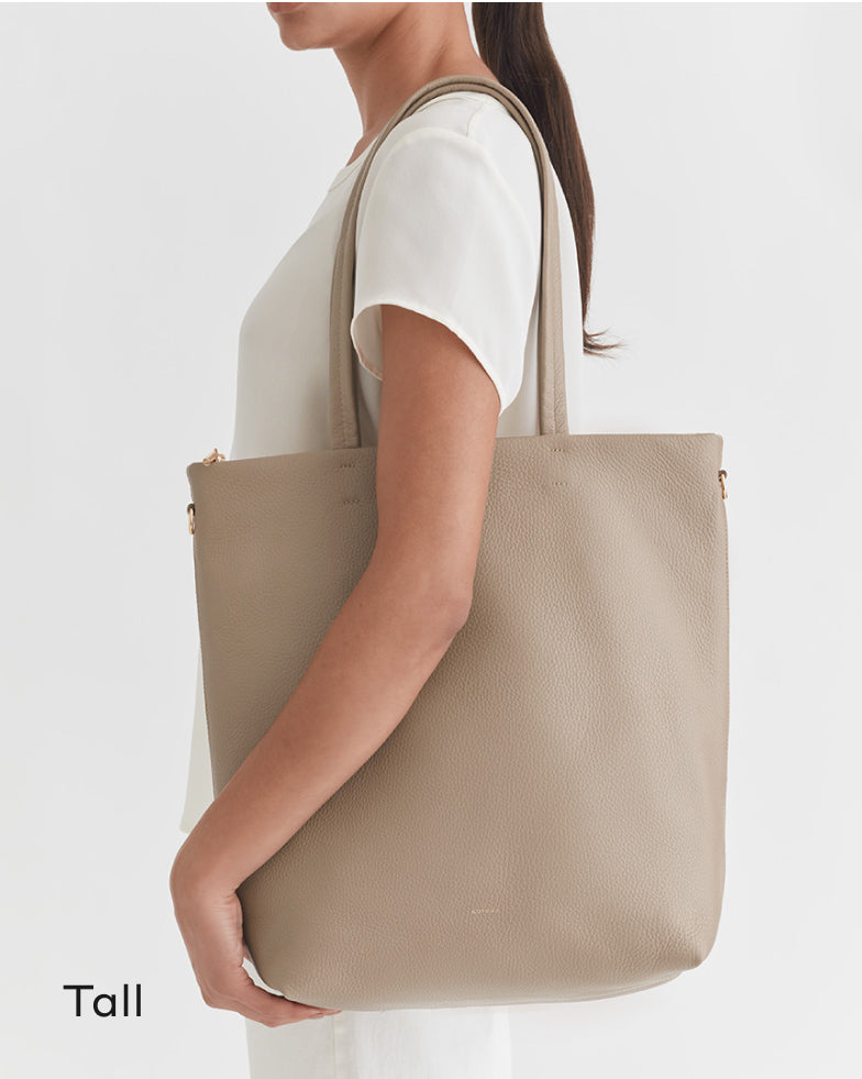 Woman wearing a top, carrying a large tote bag on her shoulder