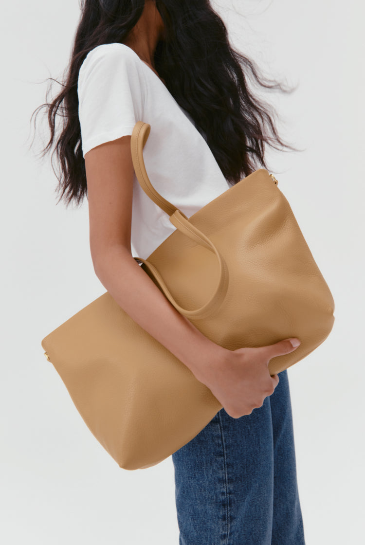 Woman holding a large handbag, wearing a t-shirt and jeans.