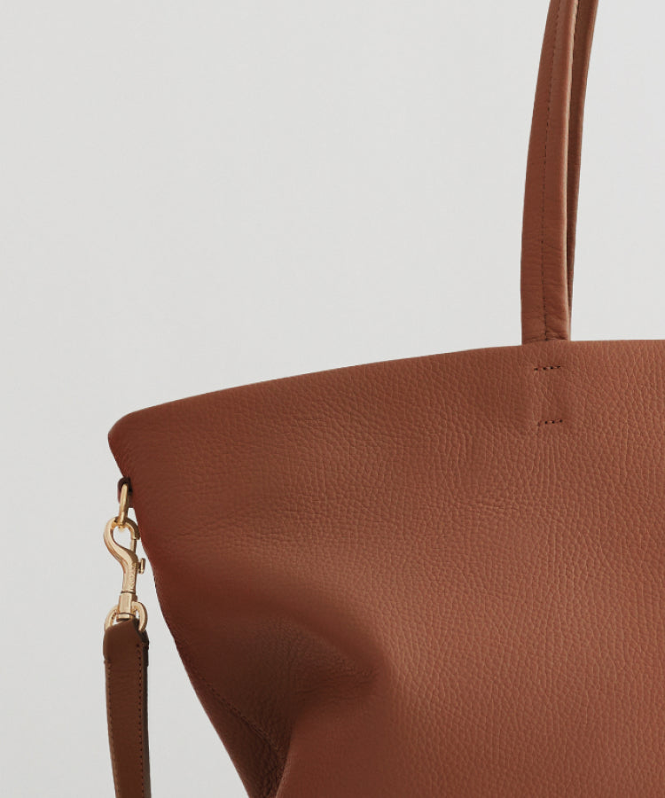 Close-up view of a part of a handbag with a strap and metal clasp.