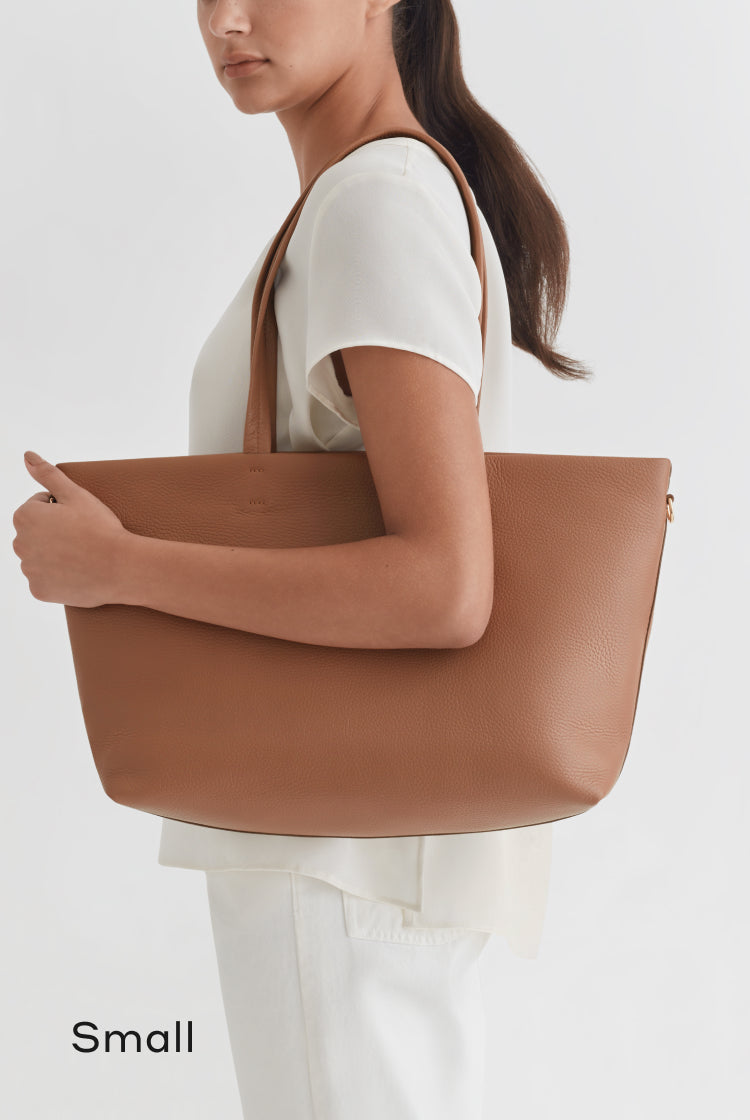 Woman carrying a large handbag, viewed from the side.