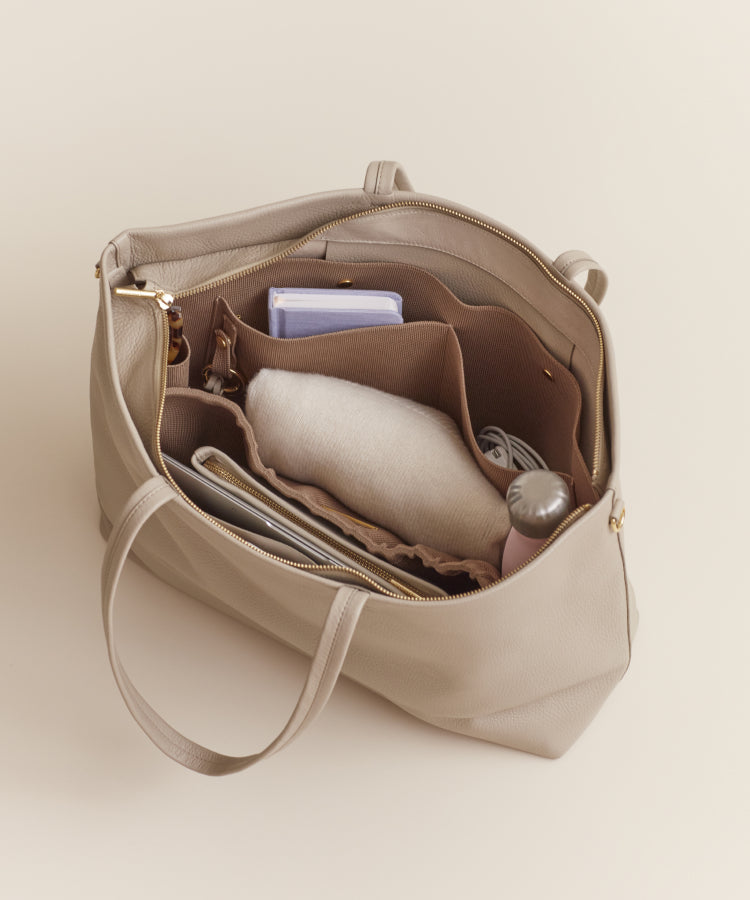 Open bag with various items inside, including a book and a blanket.