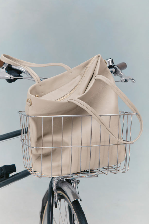 Bag in a bicycle basket, bike handlebars and part of the frame visible.