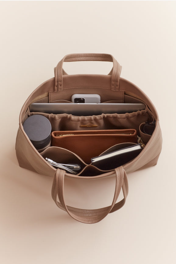 Open bag with organized compartments including a phone and sunglasses.