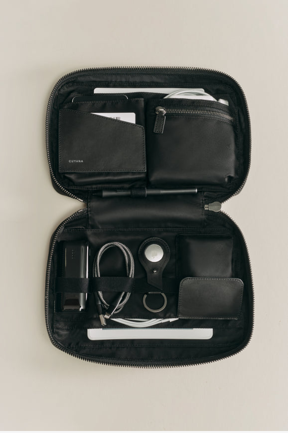 Open organizer case with various items like scissors, cables, and wallets arranged inside.