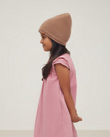 Girl in a beanie and sleeveless dress, looking to the side