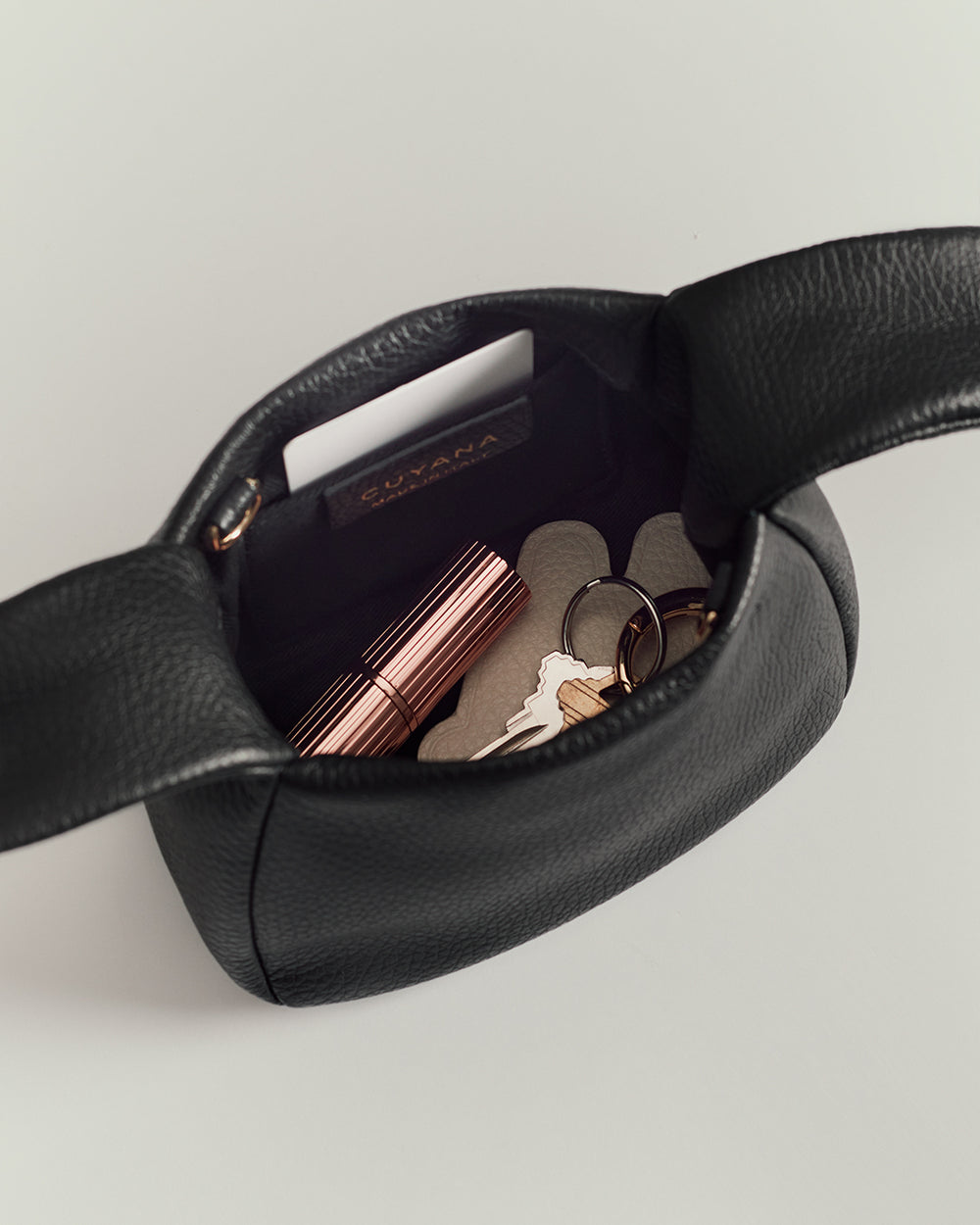 Open handbag with coins, keys, and a lipstick visible inside.