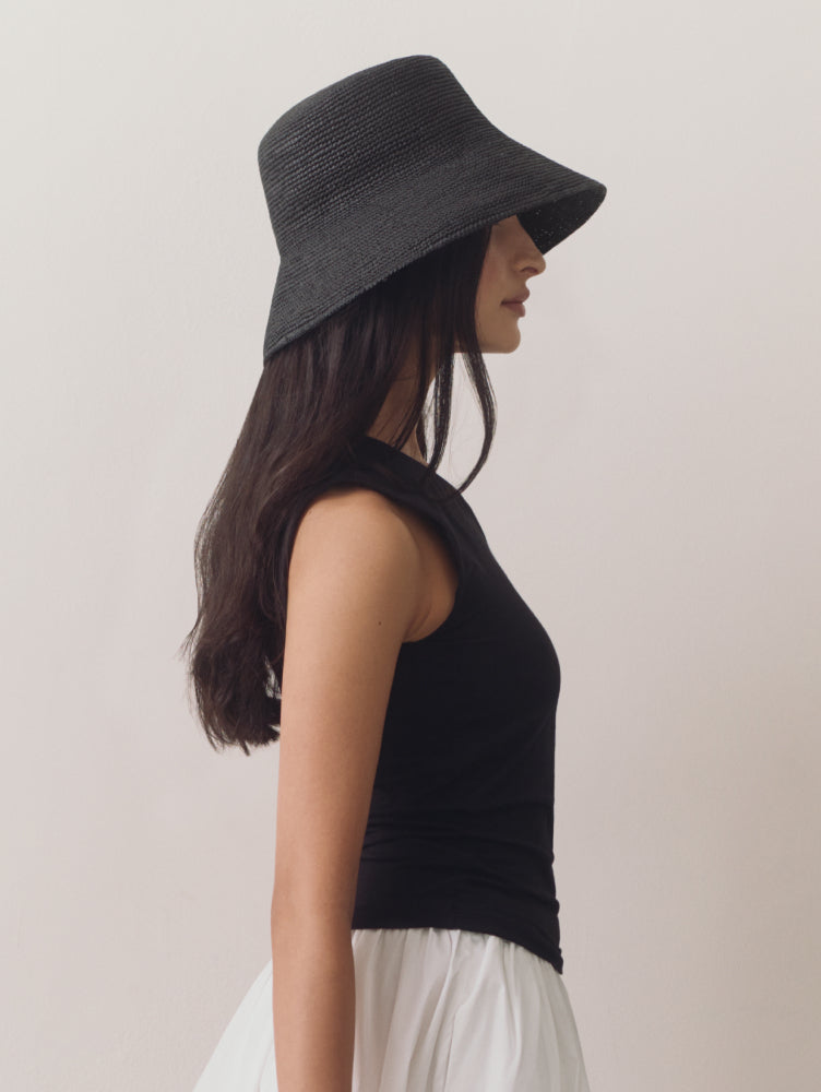 Person in sleeveless top and hat, viewed from side.