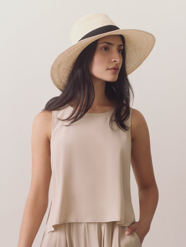 Person wearing a sleeveless top and wide-brimmed hat.