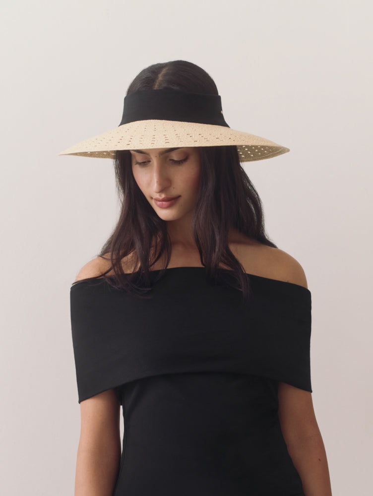 Woman in off-shoulder top wearing wide-brimmed visor looking down