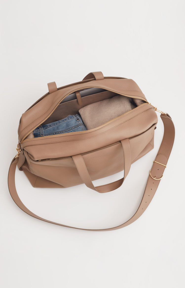 Open bag with jeans inside, shoulder strap attached.