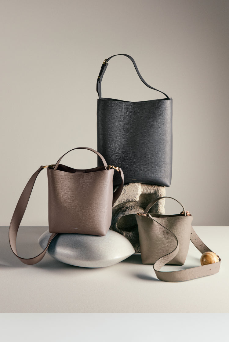 Three handbags displayed on a rounded base.