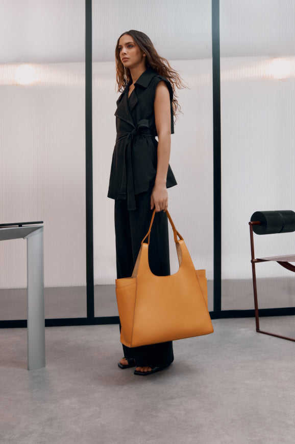 Woman standing in a modern room holding a large bag
